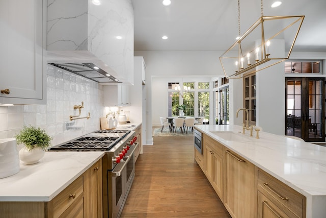 kitchen with appliances with stainless steel finishes, backsplash, ventilation hood, sink, and pendant lighting