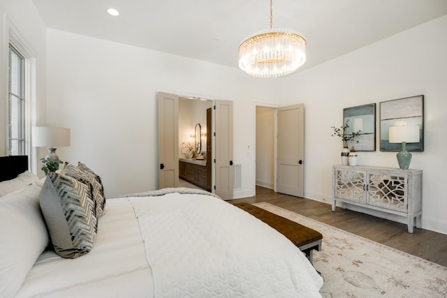 bedroom featuring connected bathroom, hardwood / wood-style flooring, and an inviting chandelier