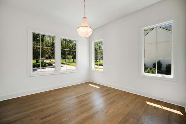 spare room with dark wood-type flooring and a notable chandelier