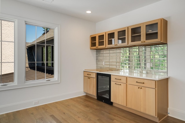 interior space with wine cooler, decorative backsplash, light brown cabinets, and light hardwood / wood-style flooring