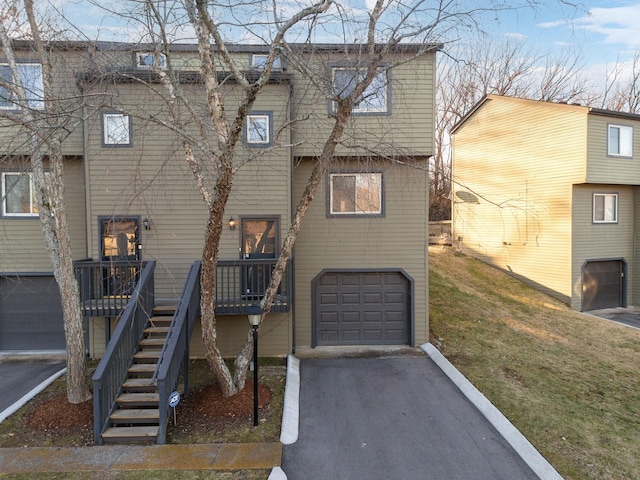 rear view of property with a yard, a garage, and a deck