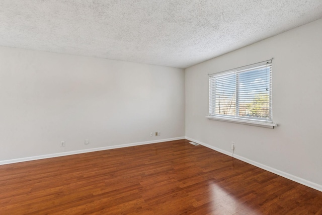 unfurnished room featuring dark wood-type flooring and a textured ceiling