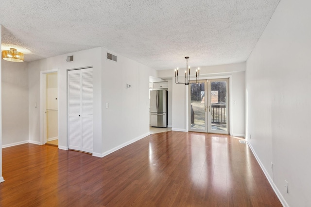 spare room featuring an inviting chandelier, hardwood / wood-style floors, and a textured ceiling