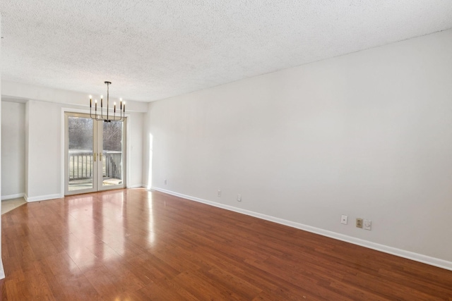 spare room featuring hardwood / wood-style floors, a textured ceiling, and a notable chandelier