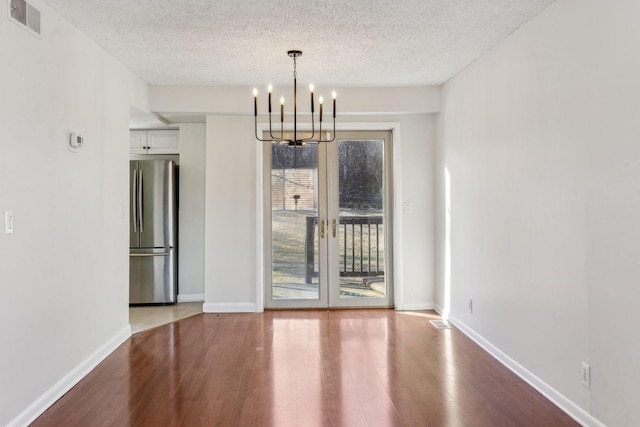 unfurnished dining area featuring an inviting chandelier, hardwood / wood-style floors, and a textured ceiling