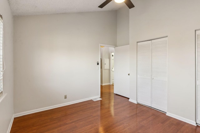 unfurnished bedroom with high vaulted ceiling, dark hardwood / wood-style floors, a textured ceiling, and ceiling fan