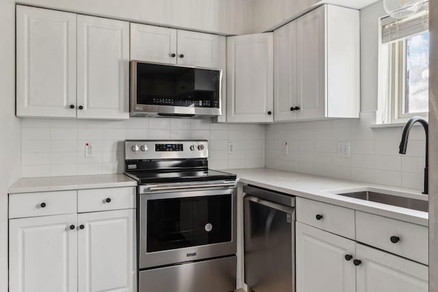 kitchen featuring white cabinetry, sink, backsplash, and stainless steel appliances