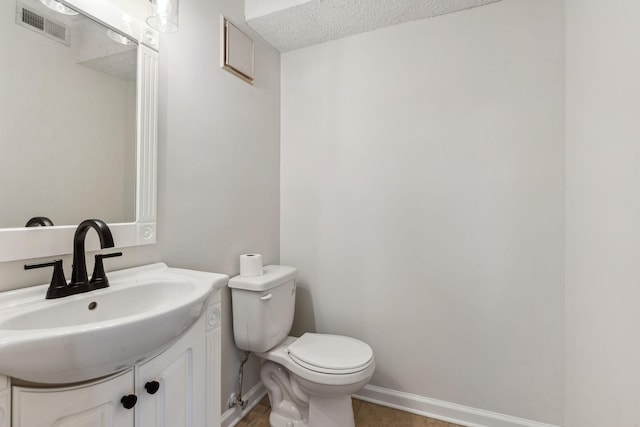 bathroom featuring vanity, toilet, and a textured ceiling