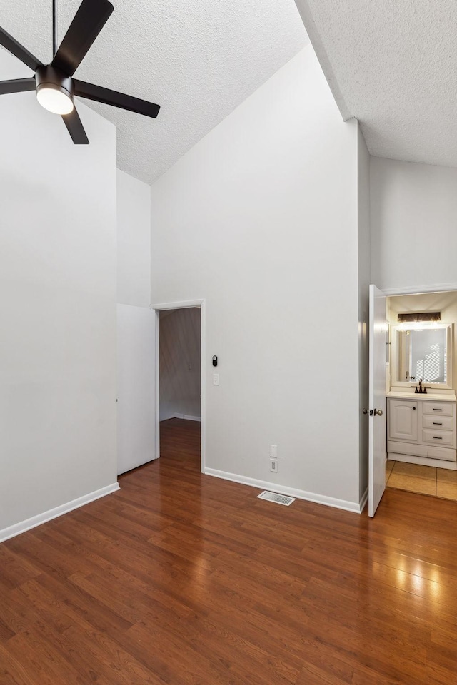 interior space featuring ceiling fan, high vaulted ceiling, a textured ceiling, and dark hardwood / wood-style flooring