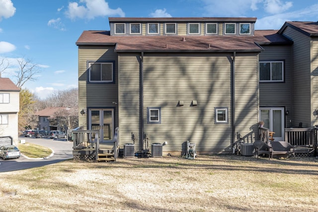 rear view of property featuring a lawn and central air condition unit