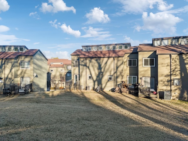 rear view of house with central AC unit and a lawn