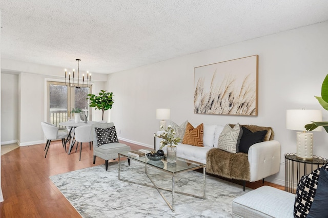 living room with an inviting chandelier, hardwood / wood-style floors, and a textured ceiling