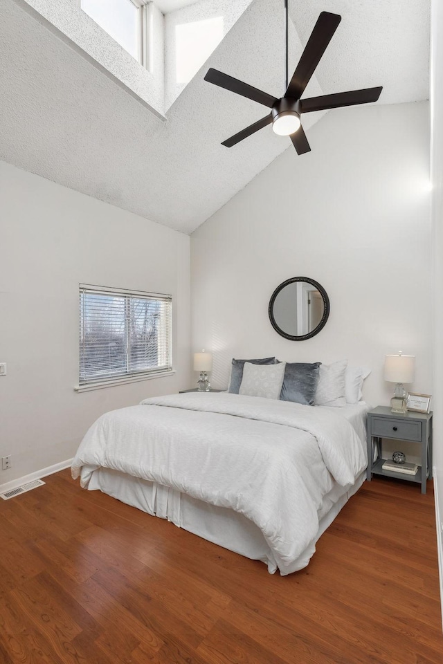 bedroom featuring ceiling fan, lofted ceiling, a textured ceiling, and dark hardwood / wood-style flooring