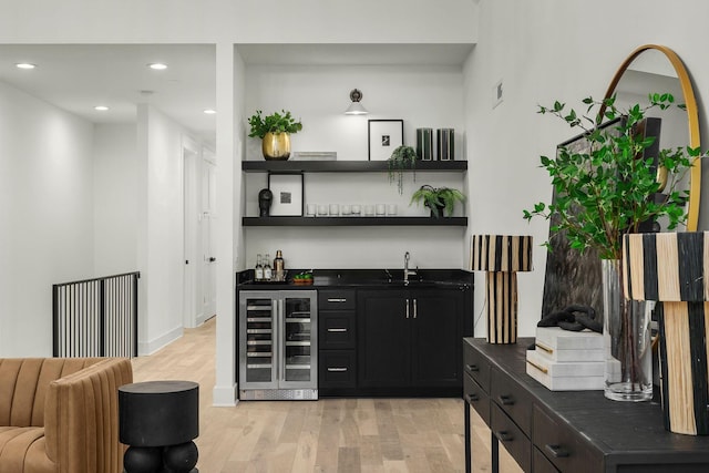 bar with wine cooler, light hardwood / wood-style flooring, and sink