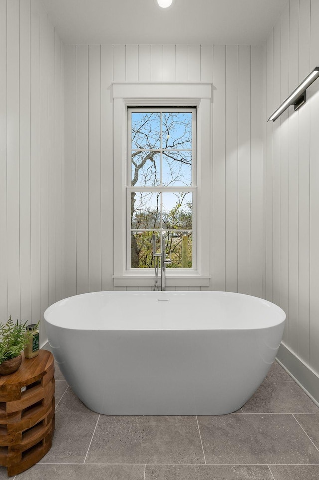 bathroom featuring wood walls and a bath