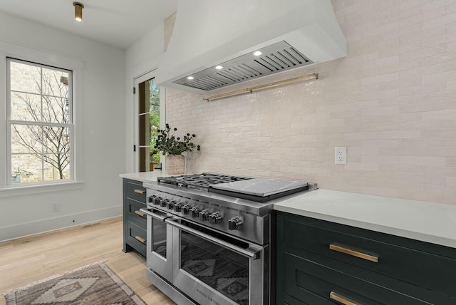 kitchen featuring decorative backsplash, light hardwood / wood-style flooring, range with two ovens, and custom exhaust hood