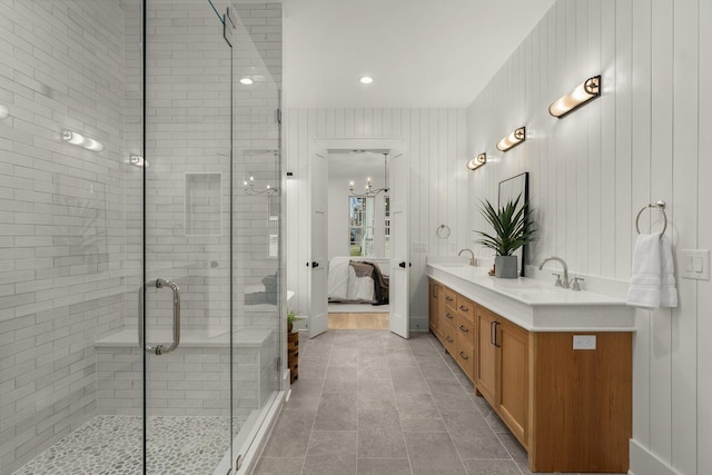 bathroom featuring tile patterned floors, wooden walls, a shower with door, and vanity