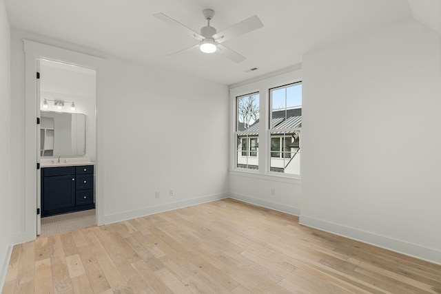 unfurnished bedroom featuring light wood-type flooring, ensuite bathroom, ceiling fan, and sink