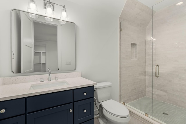 bathroom featuring vanity, toilet, and a shower with shower door