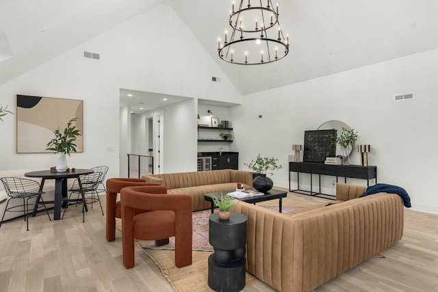 living room featuring light hardwood / wood-style flooring, high vaulted ceiling, and a chandelier