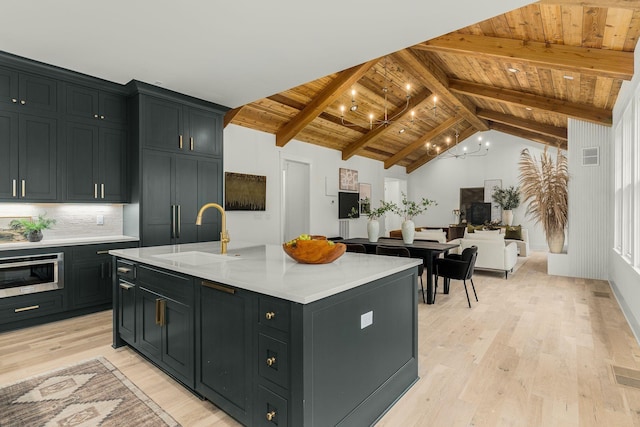 kitchen with sink, wooden ceiling, beamed ceiling, light hardwood / wood-style floors, and a kitchen island with sink