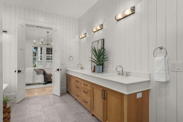 bathroom featuring wooden walls, vanity, and a notable chandelier