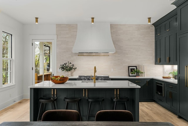 kitchen featuring light hardwood / wood-style floors, decorative backsplash, a kitchen island, and custom range hood