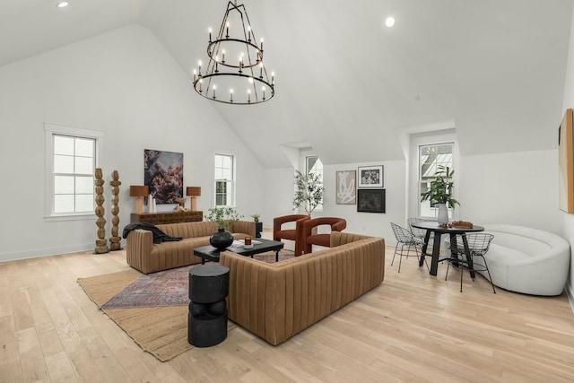 living room with a notable chandelier, high vaulted ceiling, and light hardwood / wood-style flooring