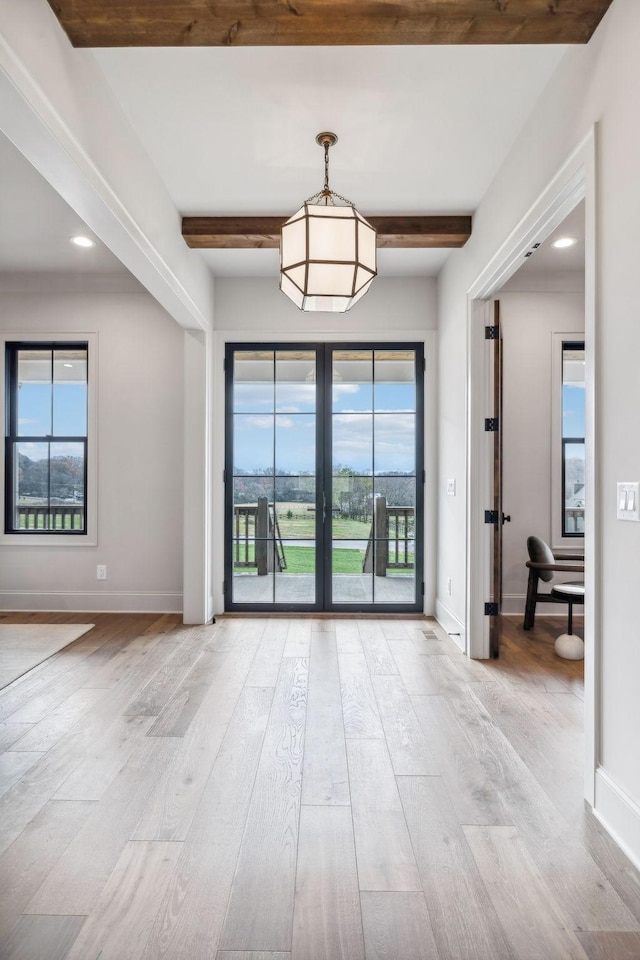 unfurnished room featuring beamed ceiling, french doors, and light wood-type flooring