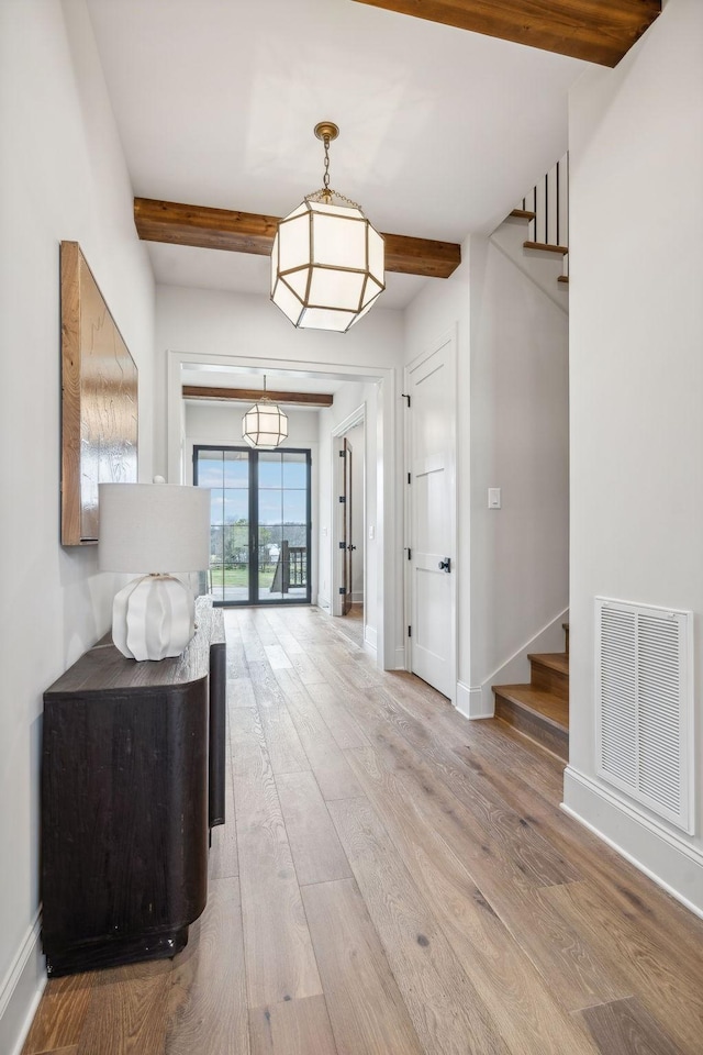 foyer with beam ceiling, french doors, and light wood-type flooring