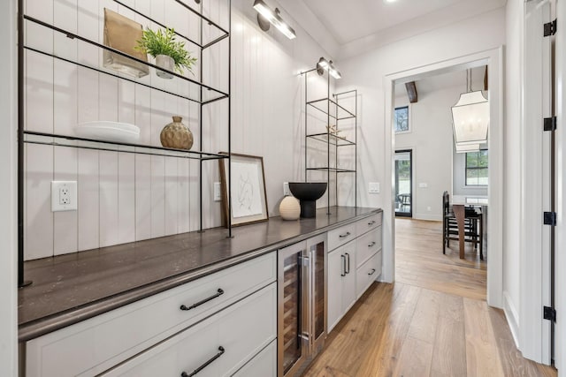 bar featuring white cabinets, beverage cooler, and light wood-type flooring