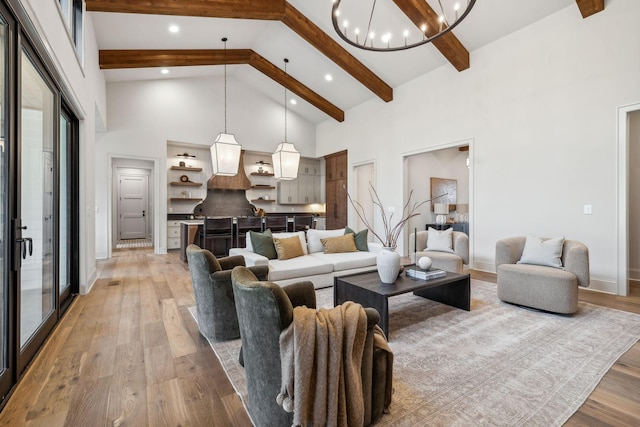 living room with beamed ceiling, an inviting chandelier, light hardwood / wood-style flooring, and high vaulted ceiling