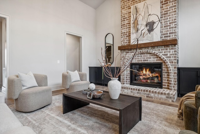 living room featuring hardwood / wood-style floors, vaulted ceiling, and a brick fireplace