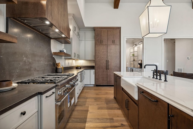 kitchen featuring light wood-type flooring, white cabinetry, custom exhaust hood, and sink