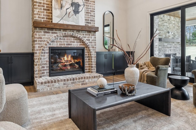 living room with light wood-type flooring and a brick fireplace