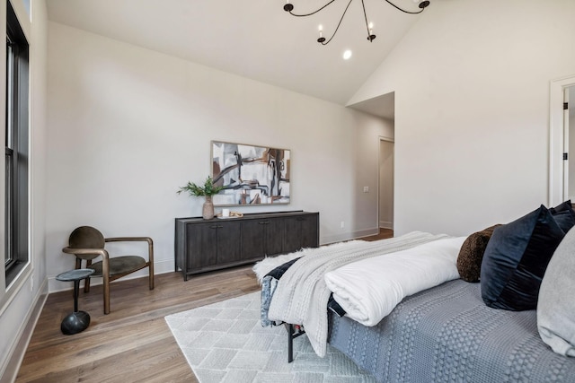 bedroom featuring a chandelier, high vaulted ceiling, and light hardwood / wood-style flooring