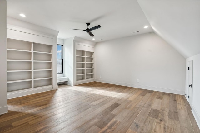 unfurnished living room with hardwood / wood-style floors, ceiling fan, vaulted ceiling, and built in shelves