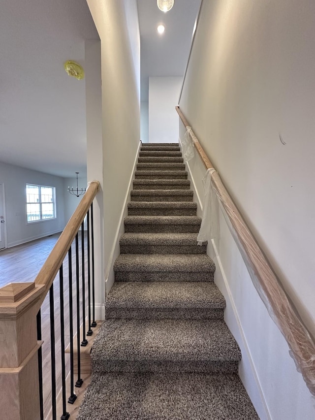 staircase featuring hardwood / wood-style floors and a chandelier