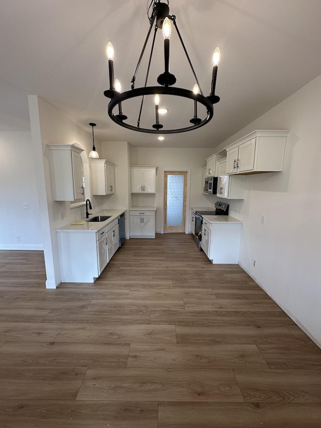 kitchen with sink, white cabinetry, stainless steel appliances, a notable chandelier, and wood-type flooring