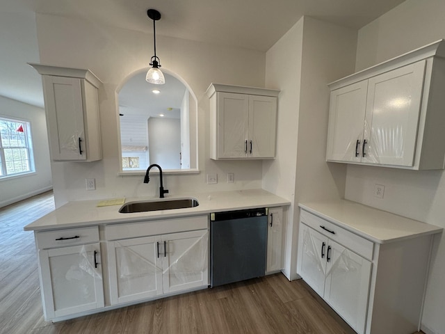 kitchen with pendant lighting, sink, hardwood / wood-style floors, black dishwasher, and white cabinets