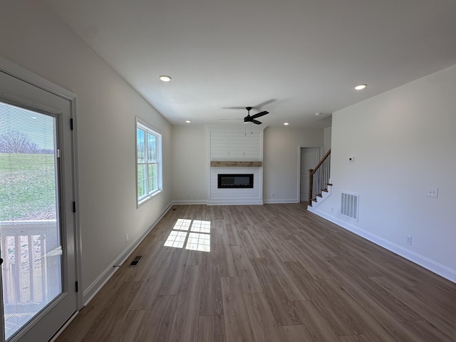 unfurnished living room with baseboards, visible vents, a ceiling fan, and wood finished floors