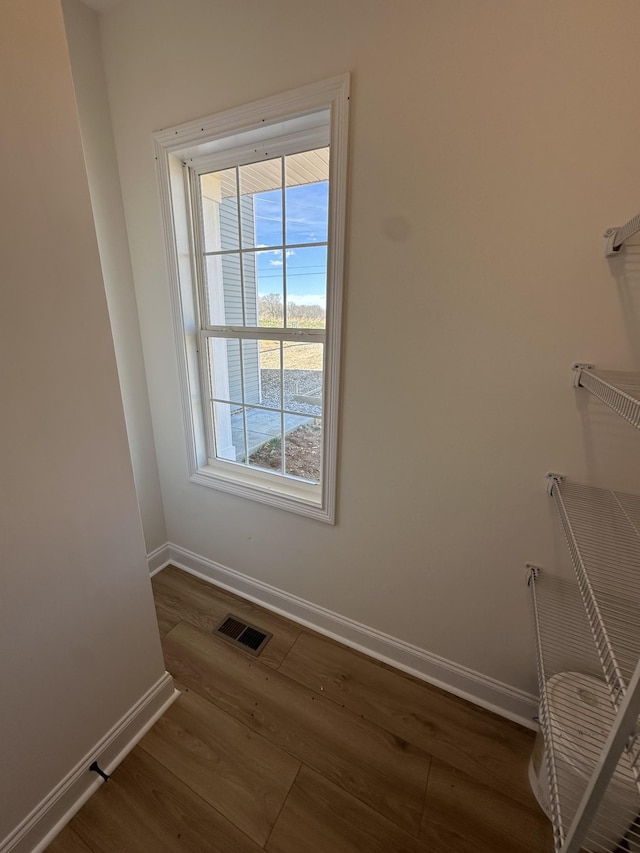 unfurnished room featuring baseboards, visible vents, and wood finished floors