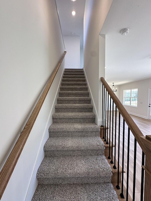 staircase featuring baseboards and wood finished floors