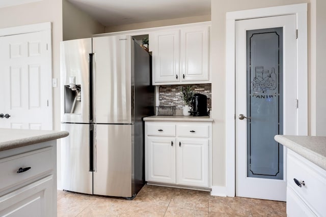 kitchen featuring white cabinets, stainless steel fridge with ice dispenser, backsplash, and light tile patterned floors