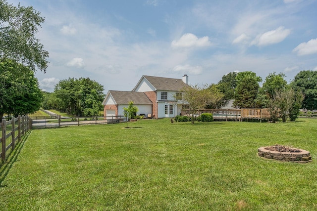 view of yard featuring a rural view, a deck, and an outdoor fire pit