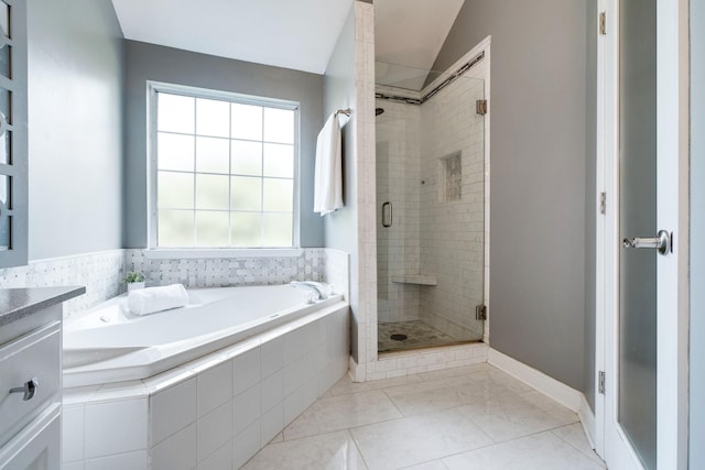 bathroom with tile patterned floors, vanity, separate shower and tub, and vaulted ceiling