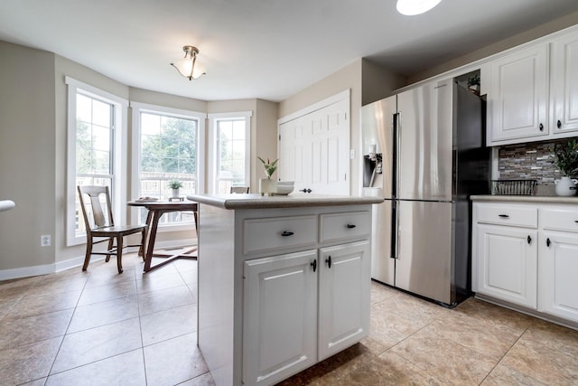 kitchen with white cabinets, decorative backsplash, light tile patterned floors, and stainless steel refrigerator with ice dispenser