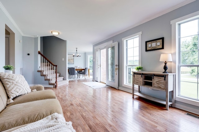 living room with hardwood / wood-style floors, a chandelier, and ornamental molding