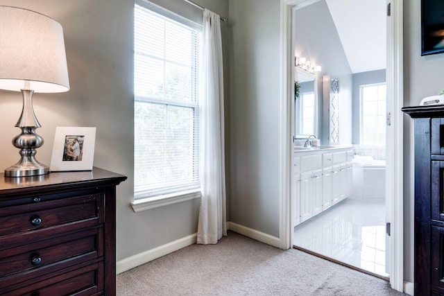 carpeted bedroom featuring multiple windows, sink, ensuite bath, and lofted ceiling