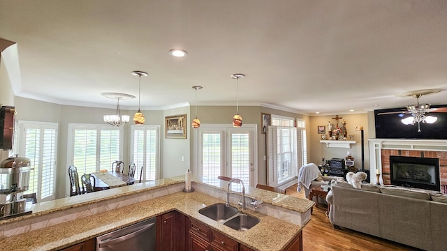 kitchen featuring a brick fireplace, ornamental molding, sink, decorative light fixtures, and dishwasher